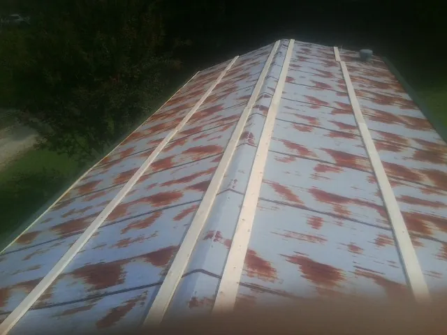 Rusted metal roof panels with new wood purlins before replacement — Storm Damage Roof Repair in Battery Park by Roofing Brothers