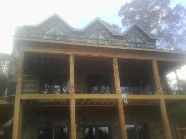 Dormers and porch framing on a large log home under construction — Roof Coating work by our crew in Battery Park