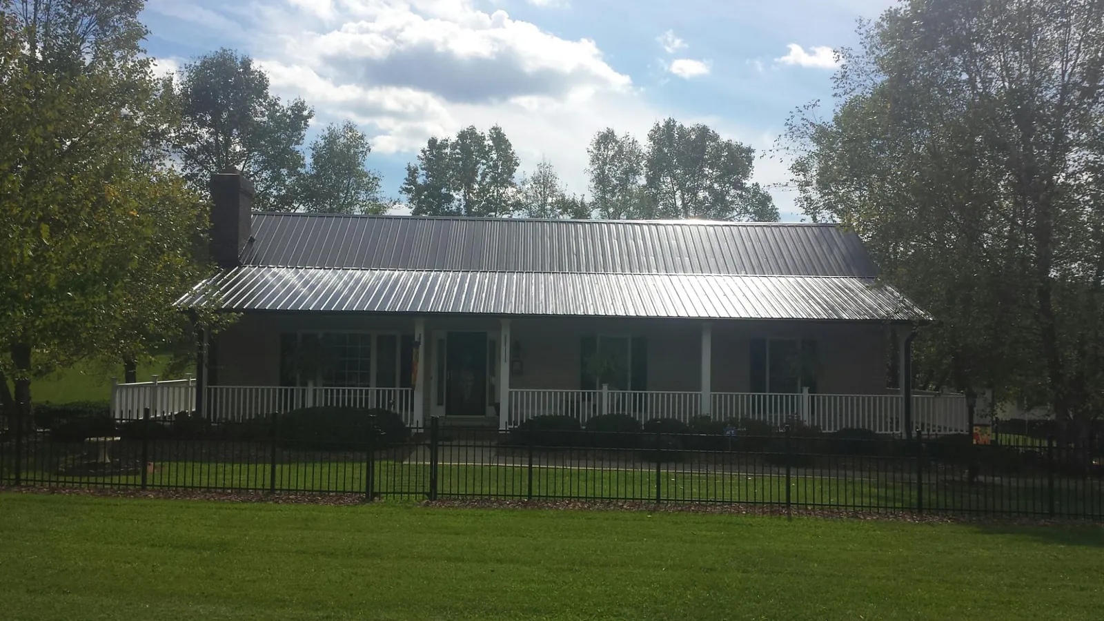 Gray metal roof on a brick ranch with a full width front porch — Gutter Guard Installation work by our crew in Battery Park