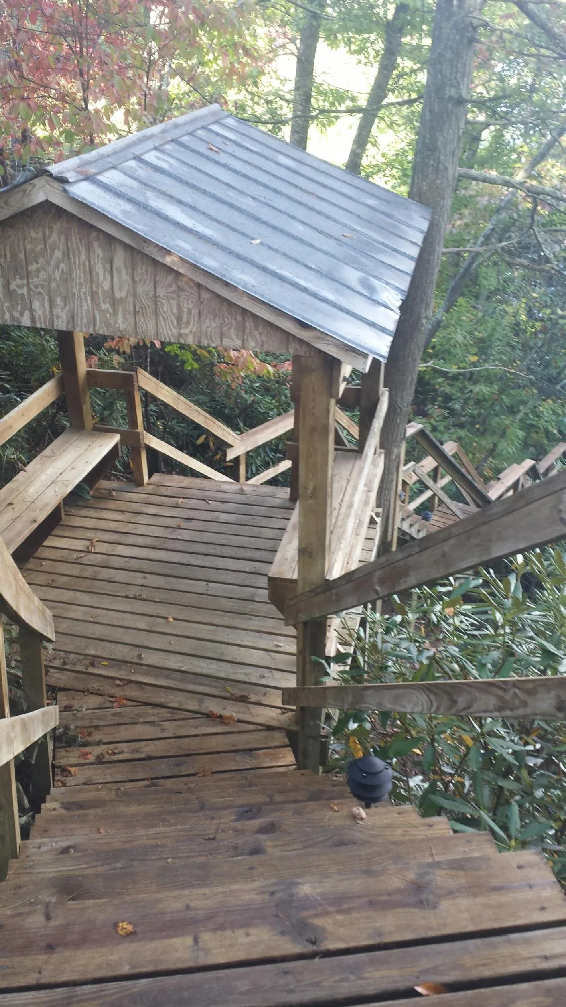 Metal roofed shelter over wooden steps on a wooded walkway — Skylight Repair & Installation work by our crew in Battery Park