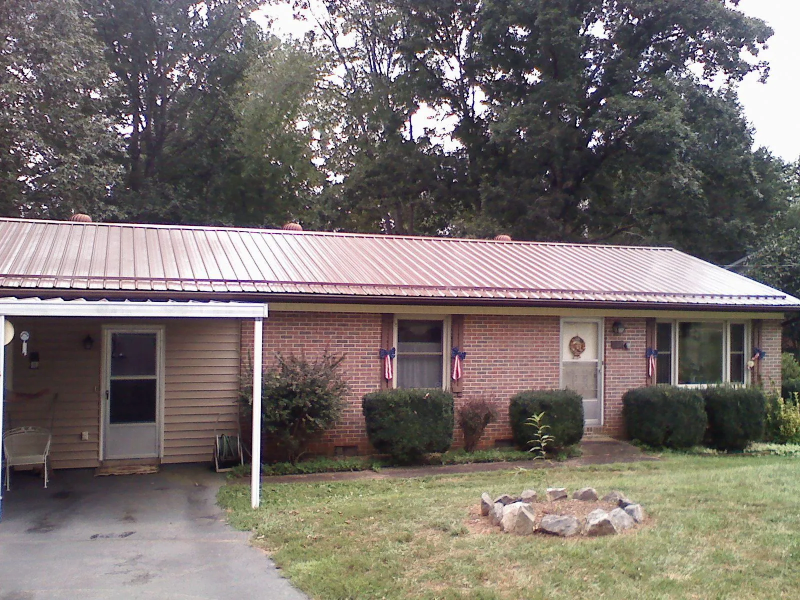 Bronze metal roof and carport on a brick ranch home — Roof Repair work by our crew in Battery Park