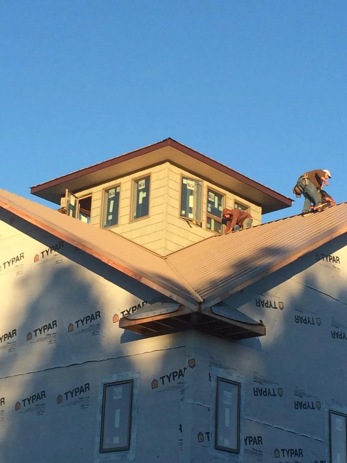 Roofers working around a rooftop cupola on a new metal roof at sunset — Roof Waterproofing in Battery Park by Roofing Brothers